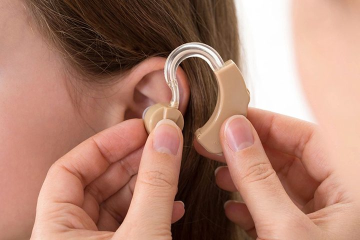 Doctor inserting hearing aid in the ear of a girl